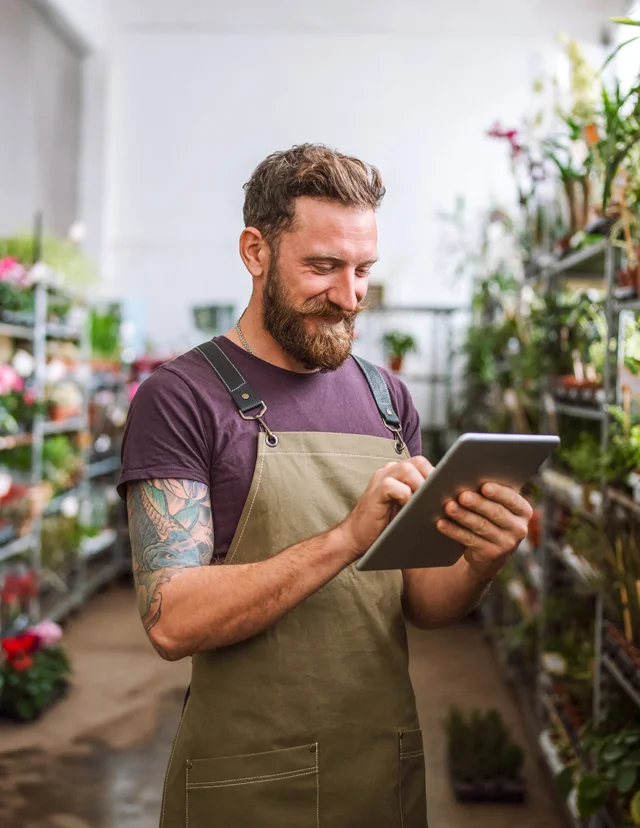 manager in garden department wearing apron holding a tablet doing inventory