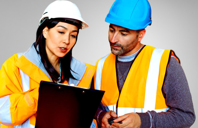two construction workers review a clipboard