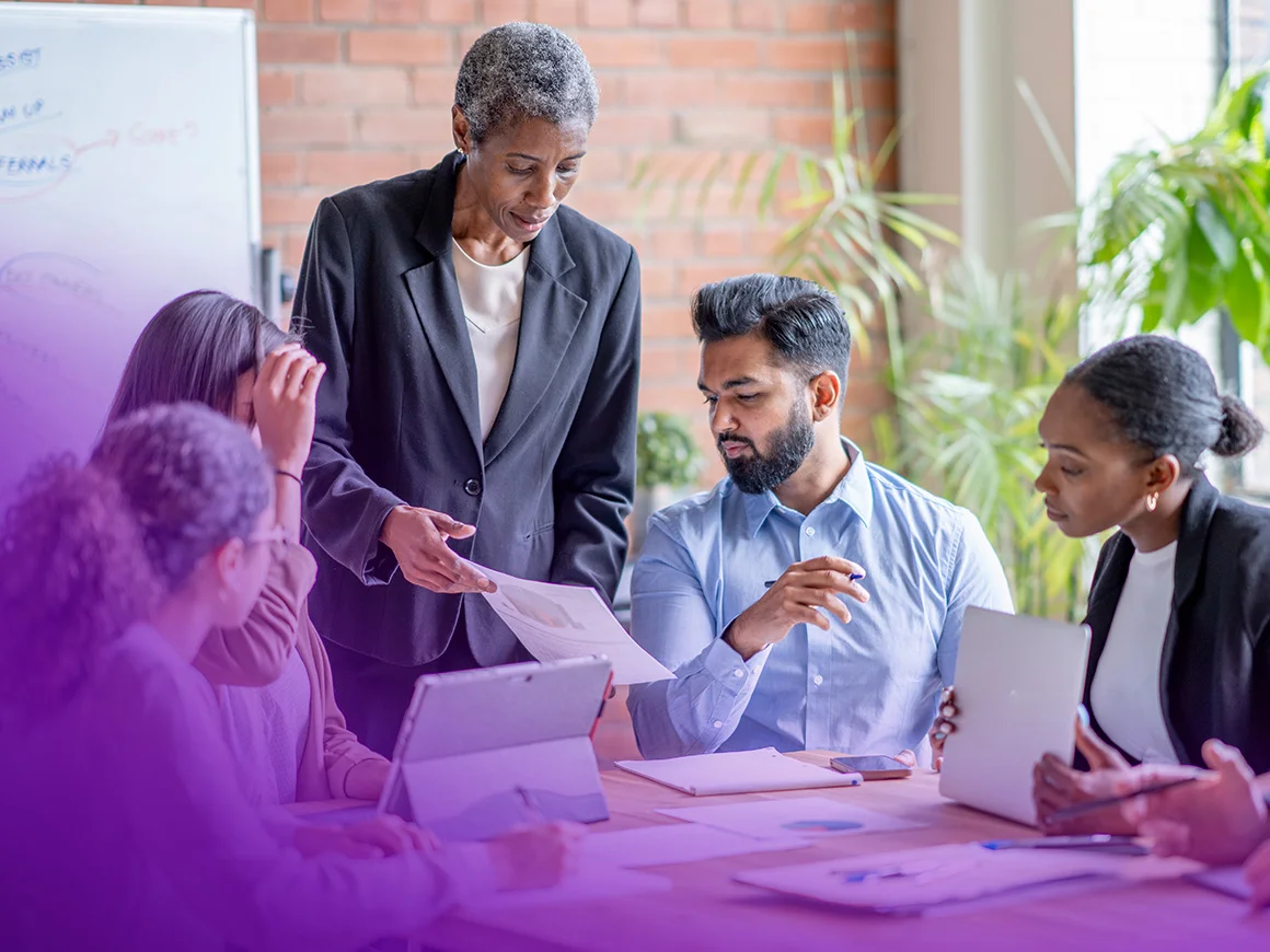 group of people around a conference table reviewing documents