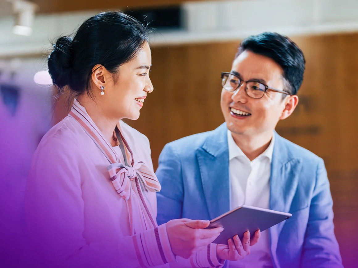 two people holding a tablet and talking