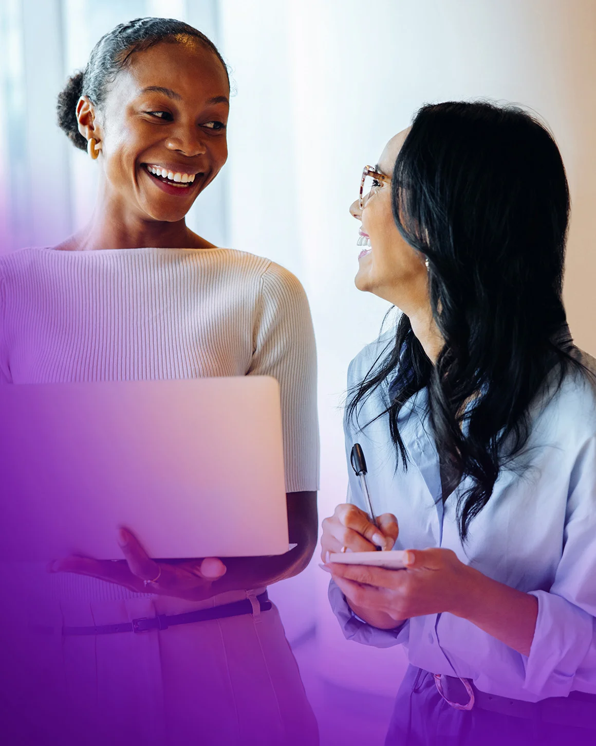 two women talking and using a laptop