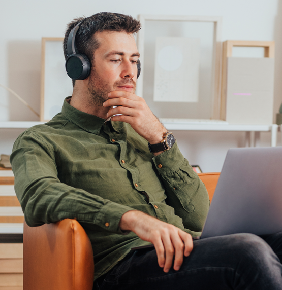 man sitting in armchair listening to podcast with his headphones